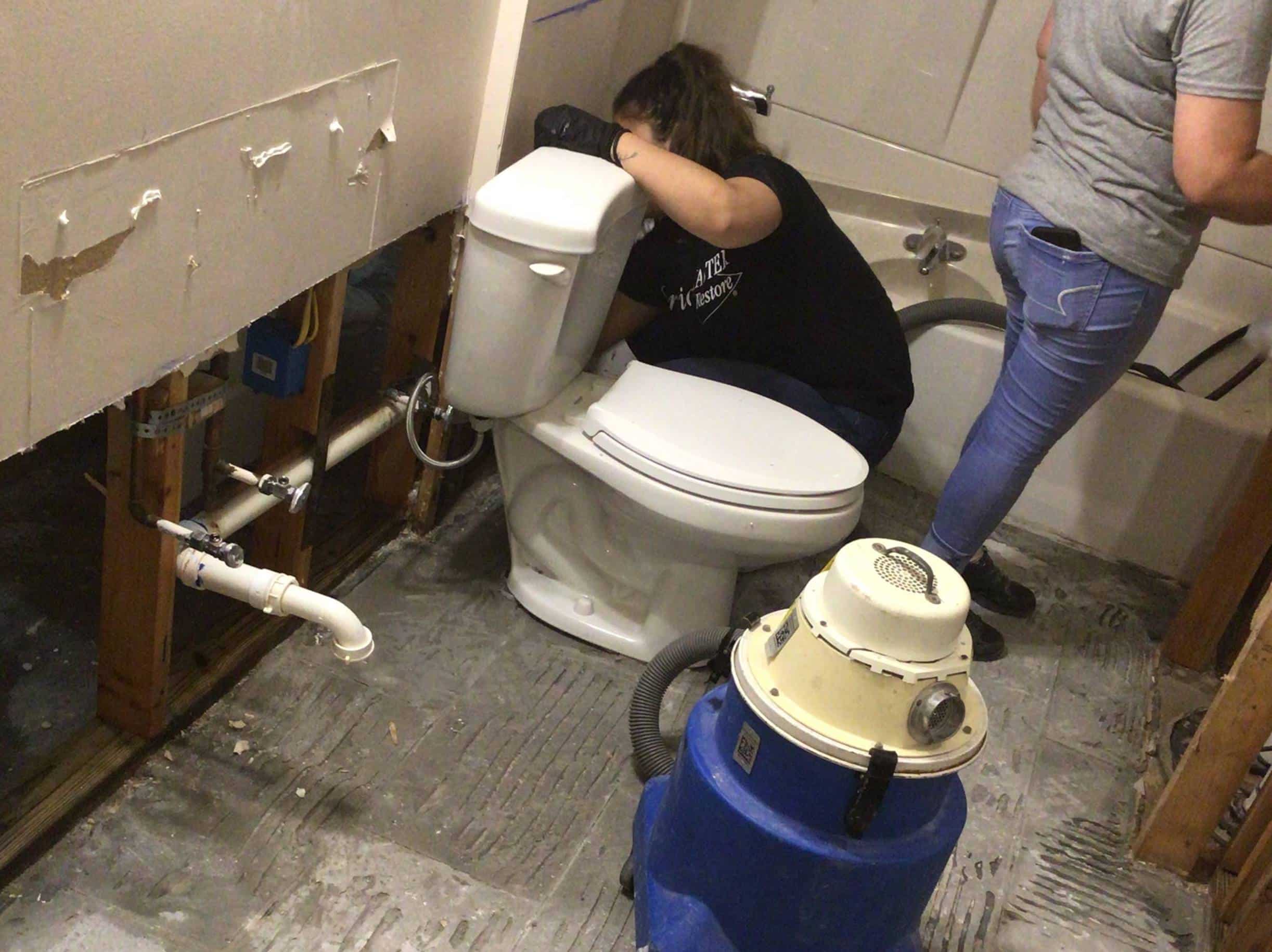 Technicians handling burst pipe in bathroom