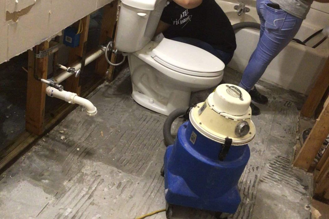 Technicians handling burst pipe in bathroom